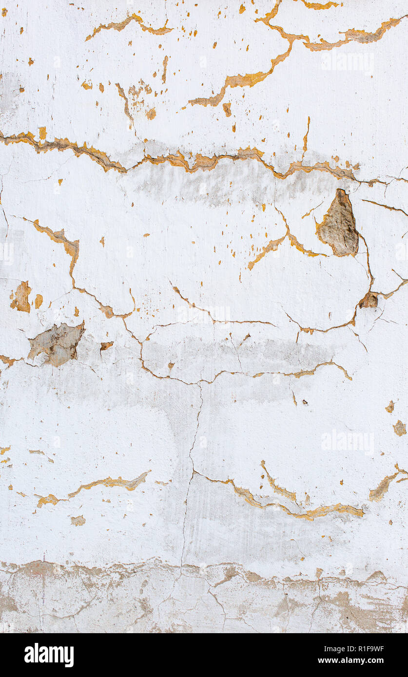 Rayé blanc mur de plâtre, arrière-plan. Vieux Mur avec des trous dans le plâtre. La texture de la surface rugueuse de stuc fissurée. Photo verticale Banque D'Images