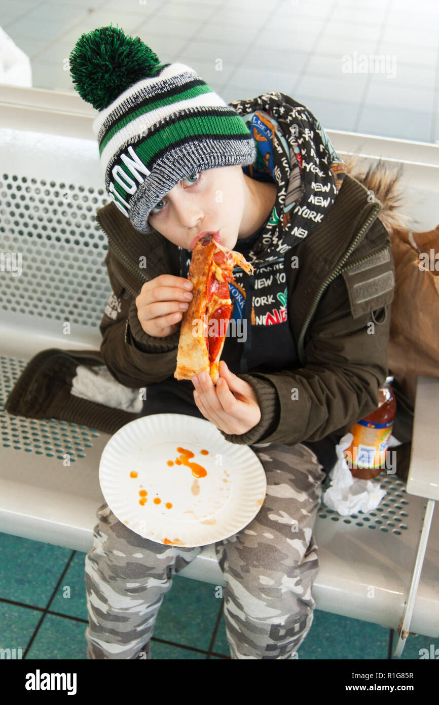 Neuf ans boy eating pizza, Staten Island Ferry Terminal, Staten Island, New York, États-Unis d'Amérique. Banque D'Images