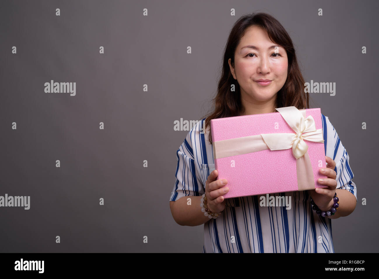 Belle asiatique mature businesswoman holding gift box Banque D'Images