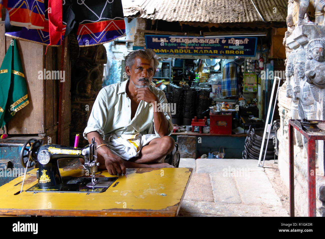Madurai, Inde - le 23 août 2018 : un tailleur dans son atelier assis à l'avant à une machine à coudre dans marché Mandapam Banque D'Images