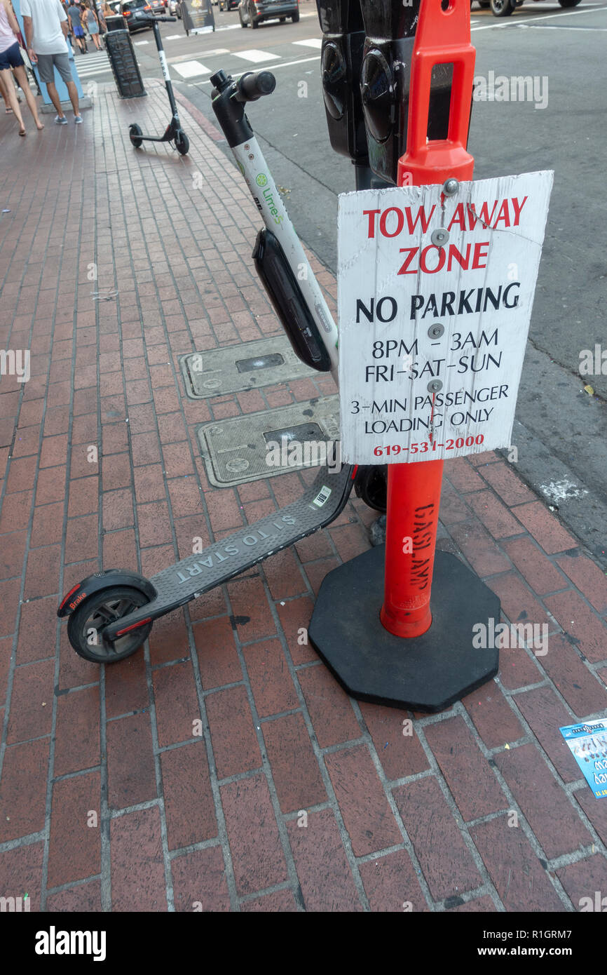 Un Tilleul S dockless scooter électrique curieusement garée à côté d'une 'Zone'-Remorquage signe, Gaslight Quarter, San Diego, California, United States. Banque D'Images Un Tilleul S dockless scooter électrique curieusement garée à côté d'une 'Zone'-Remorquage signe, Gaslight Quarter, San Diego, California, United States. Banque D'Images