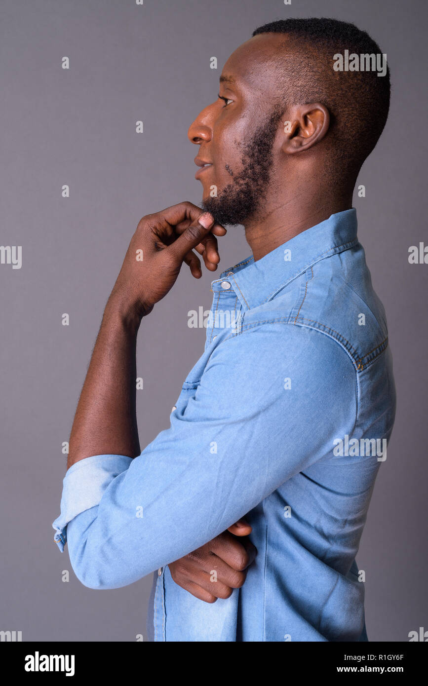 Beau jeune homme africain avec les cheveux courts contre gray backgrou Banque D'Images