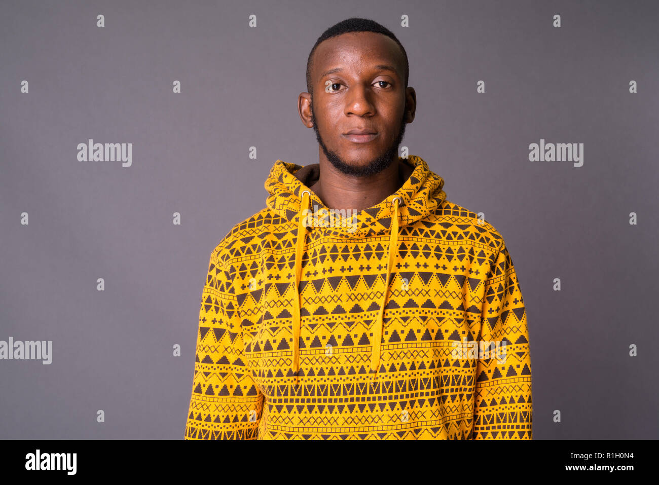 Beau jeune homme africain avec les cheveux courts contre gray backgrou Banque D'Images