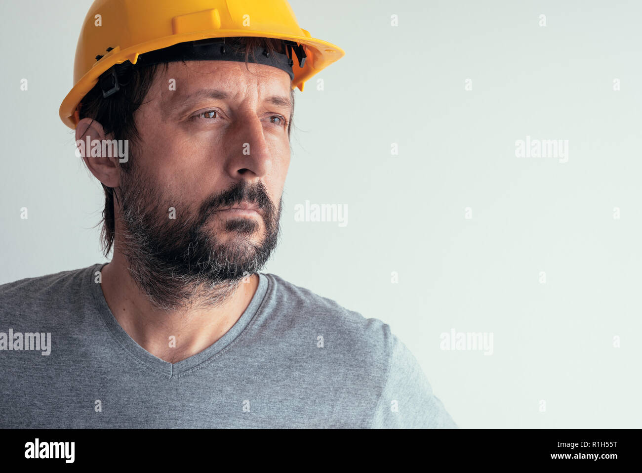 Portrait de l'ingénieur de la construction réfléchie grave isolé sur fond lumineux Banque D'Images