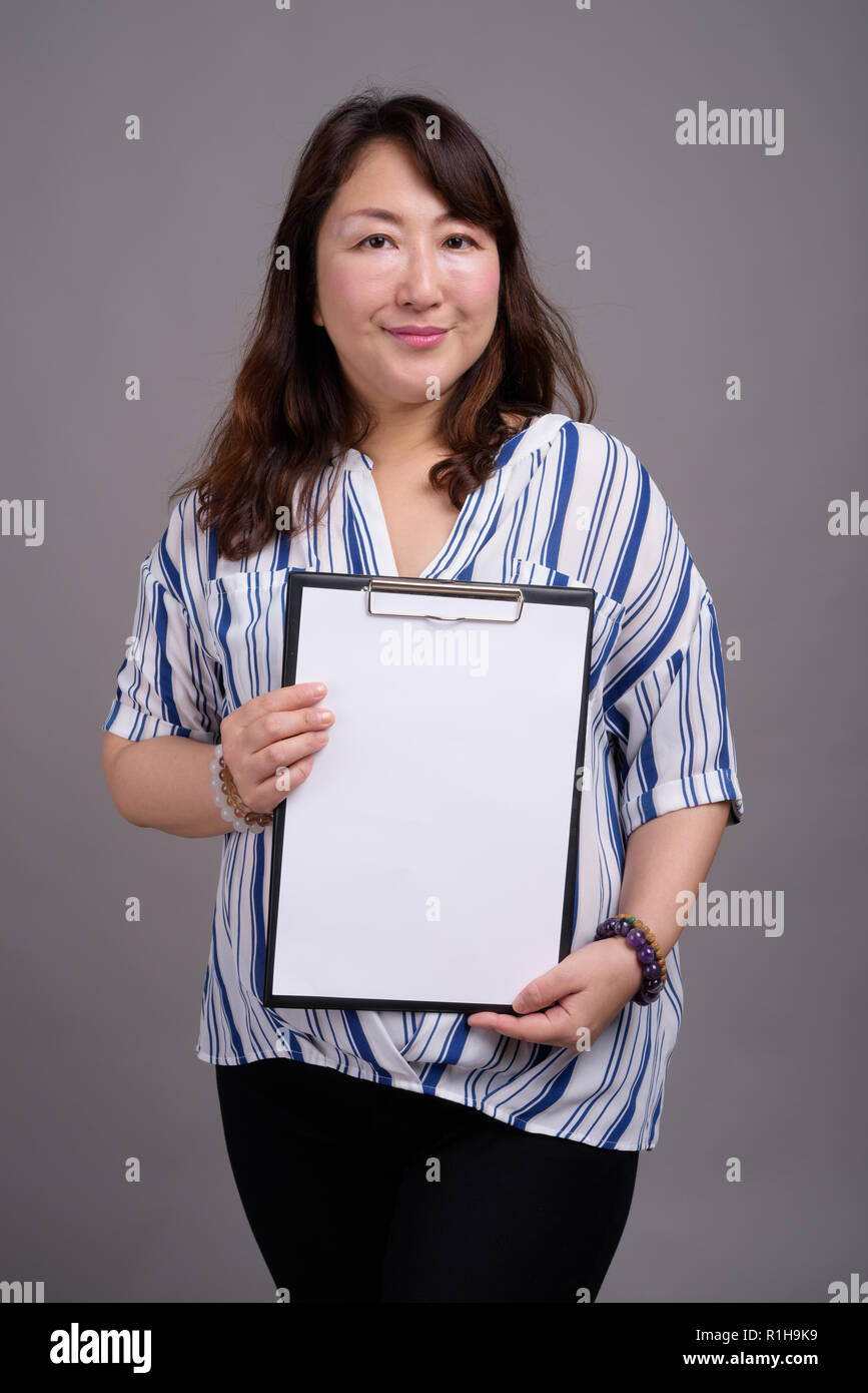Japanese businesswoman holding clipboard avec papier blanc vide Banque D'Images