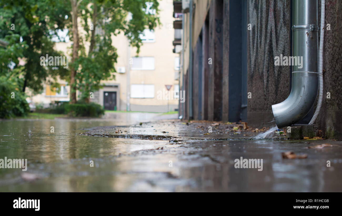 C'est la descente d'évacuer l'eau sur une chaussure de descente tout droit dans une rue inondée. Quelques gouttes sont frappant une surface d'une flaque. Focus sélectif. Banque D'Images