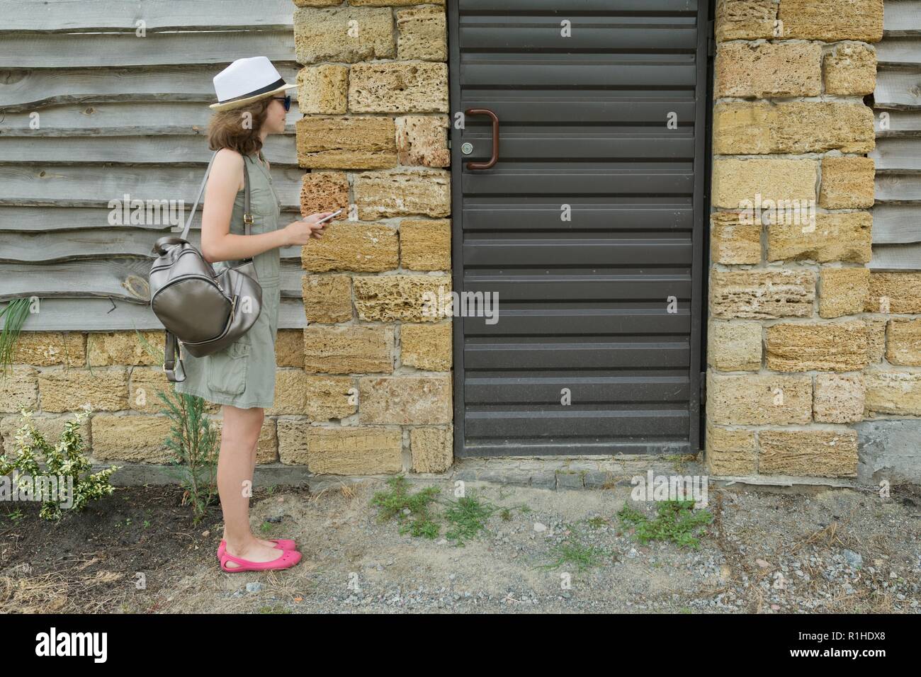 Appels de l'interphone extérieur girl, debout près de la porte avant. Banque D'Images