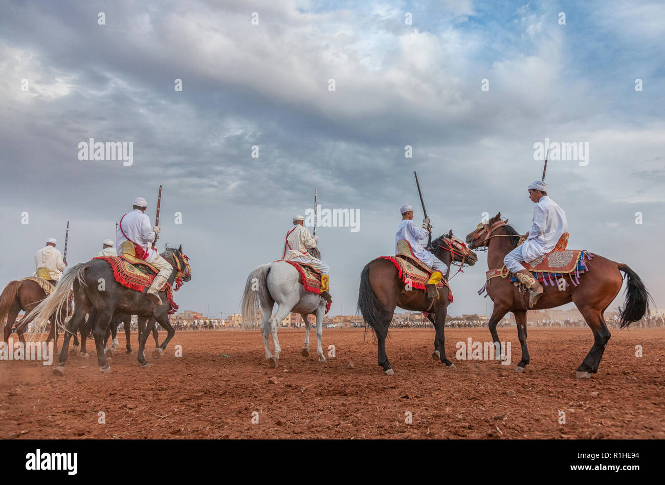 Un groupe de cavaliers, vêtu de vêtements traditionnels et de charge le long d'un chemin droit dans un show appelé Tbouria ou Fantasia Banque D'Images