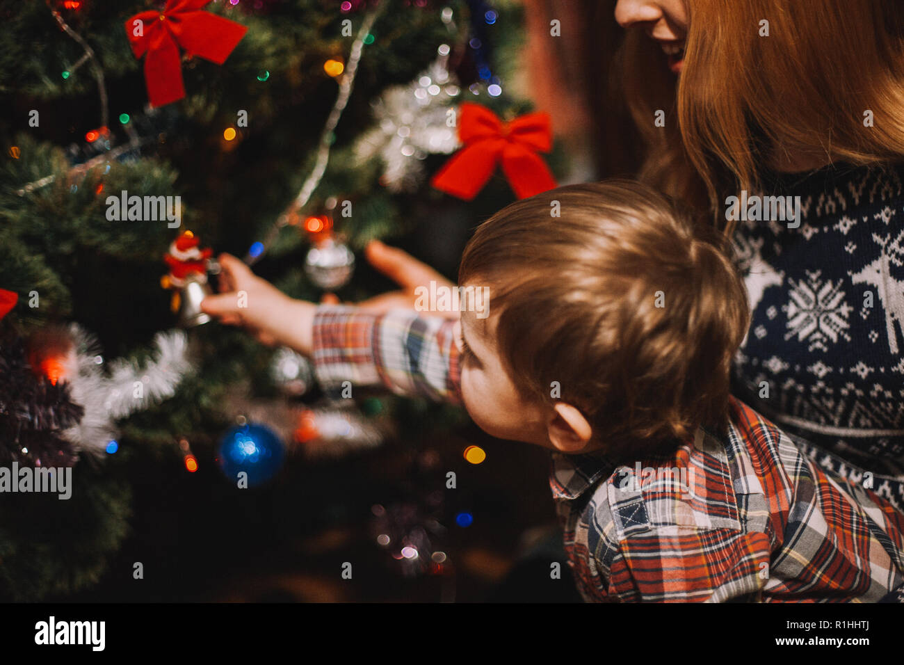 Mère Noël montrant à bell baby boy alors qu'assis à côté d'arbre de Noël à la maison Banque D'Images