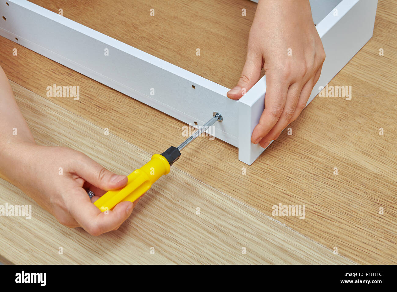 L'assembleur de meubles serre la vis dans un tiroir d'aggloméré de bois à  l'aide d'un tournevis, de meubles prêts-à-assembler Photo Stock - Alamy