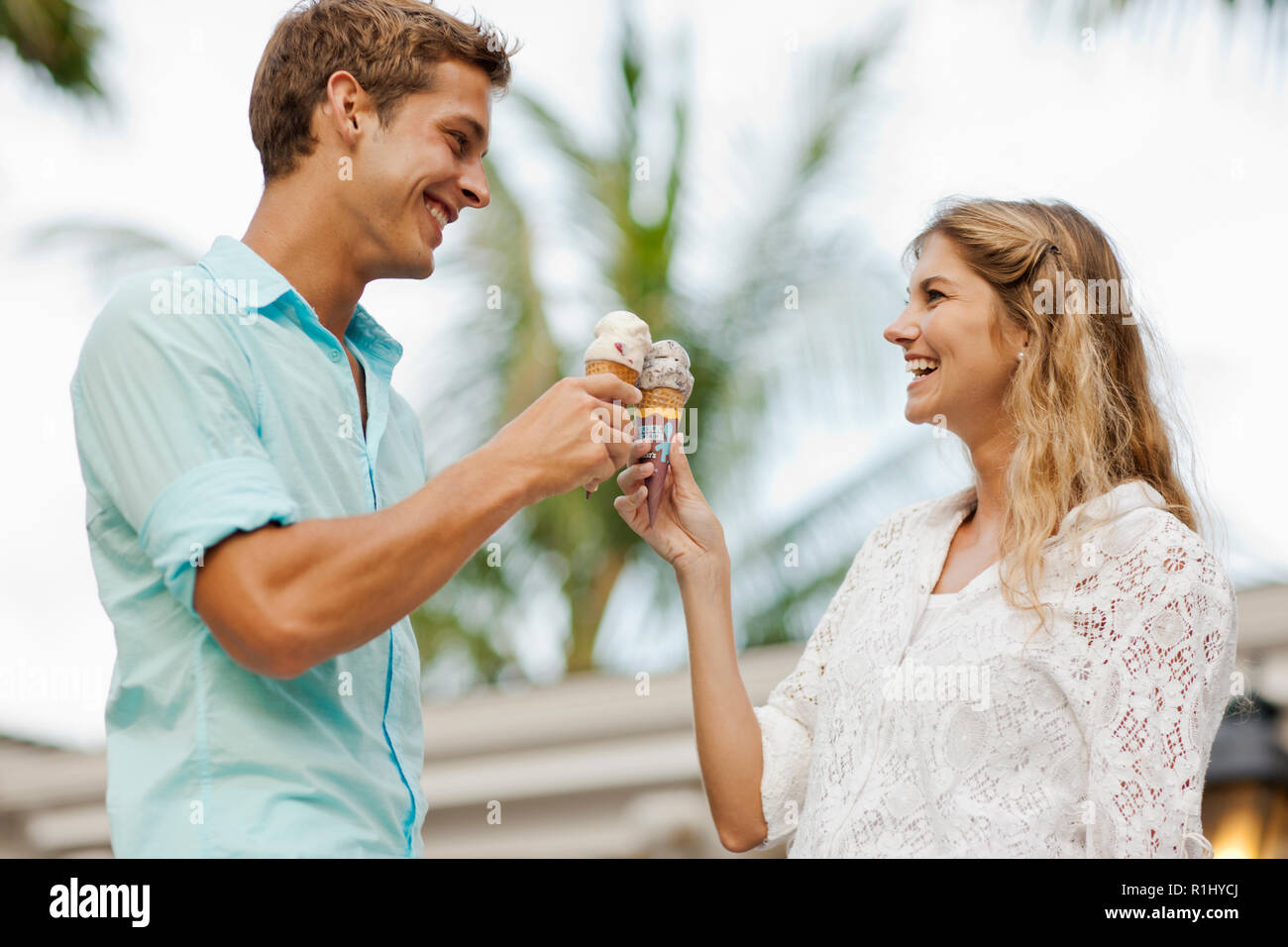 Smiling young couple toasting each other with leurs cornets de crème glacée. Banque D'Images