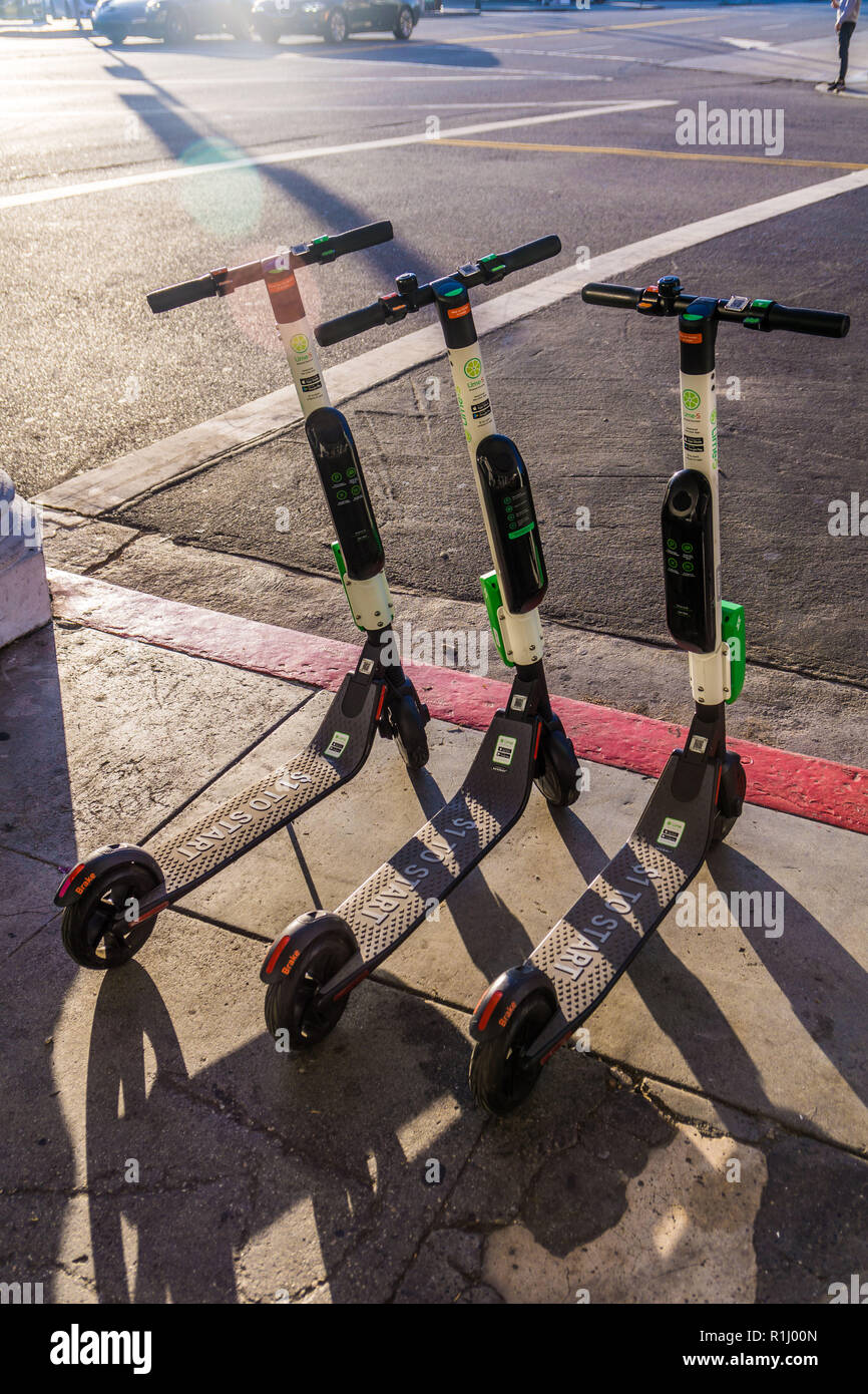 Un groupe de la chaux des scooters électriques en attente pour les cavaliers à Venice Beach Banque D'Images