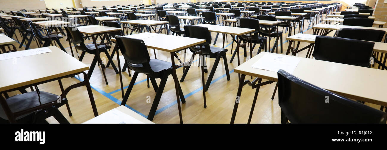 Vue d'un grand hall de la salle d'examen et de l'examen bureaux tables alignées en rangées prêt pour les étudiants d'une école secondaire pour venir s'asseoir leurs examens papier tests Banque D'Images