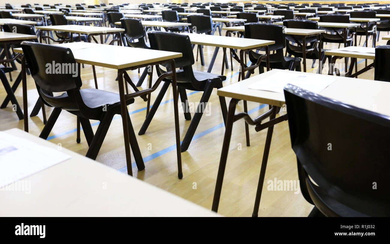 Vue d'un grand hall de la salle d'examen et de l'examen bureaux tables alignées en rangées prêt pour les étudiants d'une école secondaire pour venir s'asseoir leurs examens papier tests Banque D'Images