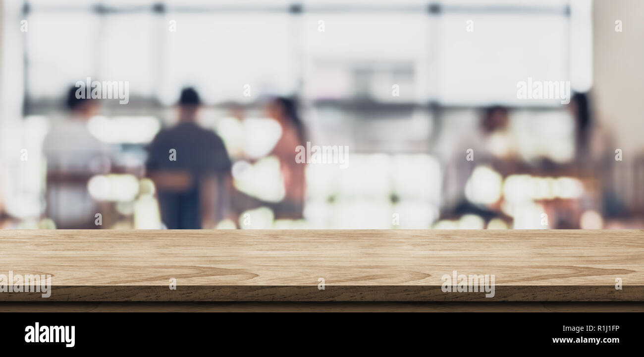 Table en bois vide avec blur coffee shop dans la lumière d'arrière-plan flou et de feuilles,de premier plan des maquettes pour l'affichage ou un montage de produit,bannière pour adver Banque D'Images