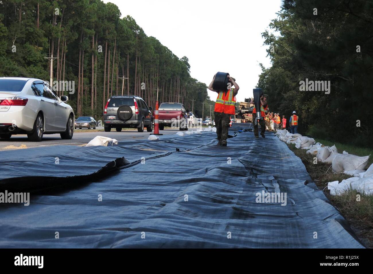 Des soldats américains avec la Compagnie Alpha, 1er Bataillon, 118e Régiment d'infanterie, la Garde nationale de Caroline du Sud portent les flexibles pour la mise en place d'un AquaDam sur la route 17 dans le comté de Georgetown, Caroline du Sud, 25 septembre 2018. Les soldats aident Caroline du sud Ministère des transports avec la mise en place de l'AquaDam à garder les routes ouvertes pendant la montée des eaux dans la zone après l'ouragan Florence. Environ 2 000 soldats de la Garde nationale de Caroline du Sud et les aviateurs sont actuellement en service des autorités locales dans l'intervention et le rétablissement de la paix à l'inondation qui a suivi l'Ouragan Flo Banque D'Images