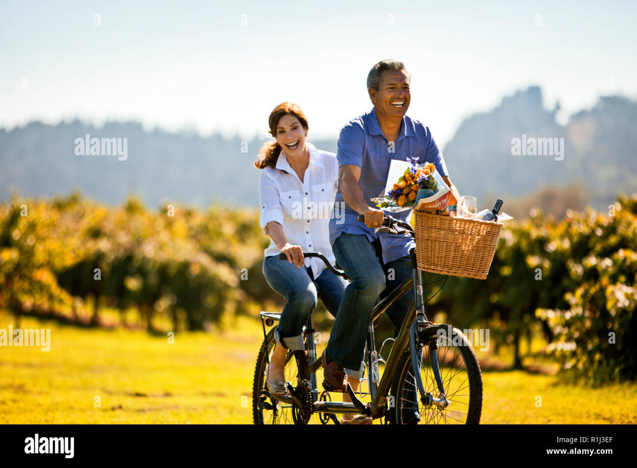 Middle-aged woman having fun riding la location avec son mari dans le vignoble. Banque D'Images