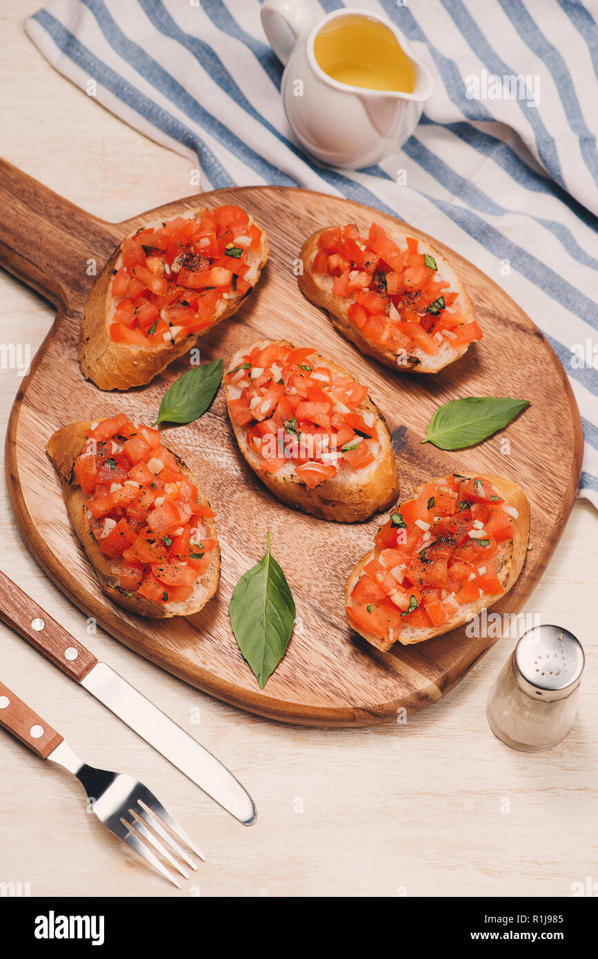 Bruschetta italienne avec pain garni d'herbes et de tomates sur planche de bois Banque D'Images