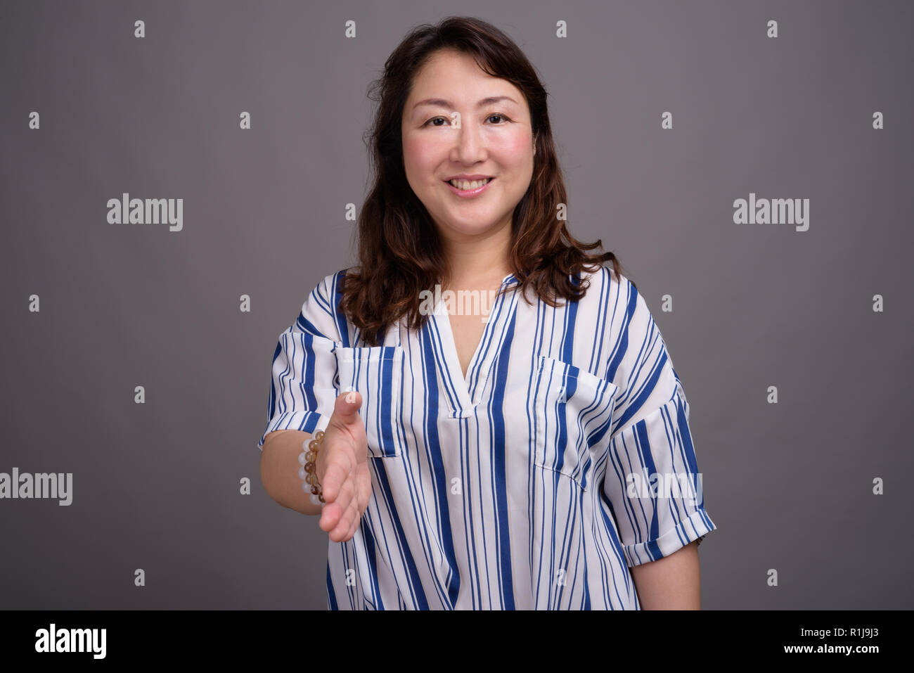 Belle mature Asian businesswoman contre l'arrière-plan gris Banque D'Images