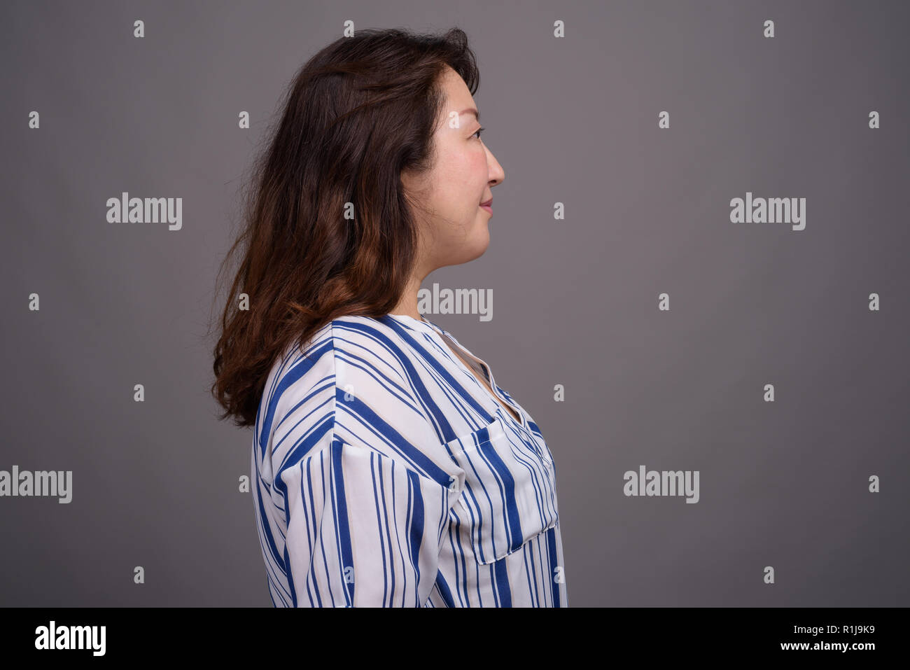 Belle mature Asian businesswoman contre l'arrière-plan gris Banque D'Images