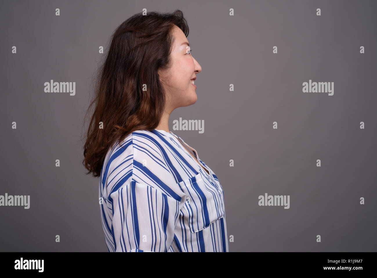 Belle mature Asian businesswoman contre l'arrière-plan gris Banque D'Images