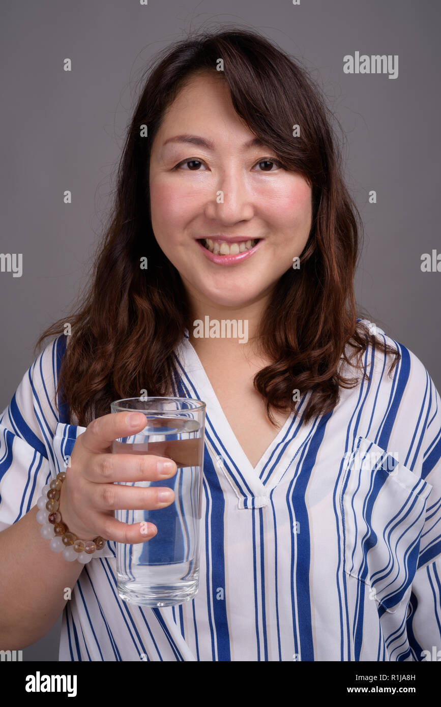 Belle asiatique mature woman holding glass of water Banque D'Images