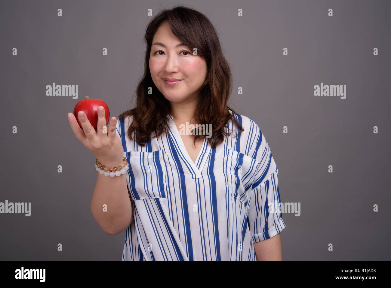 Belle asiatique mature businesswoman holding apple en bonne santé Banque D'Images