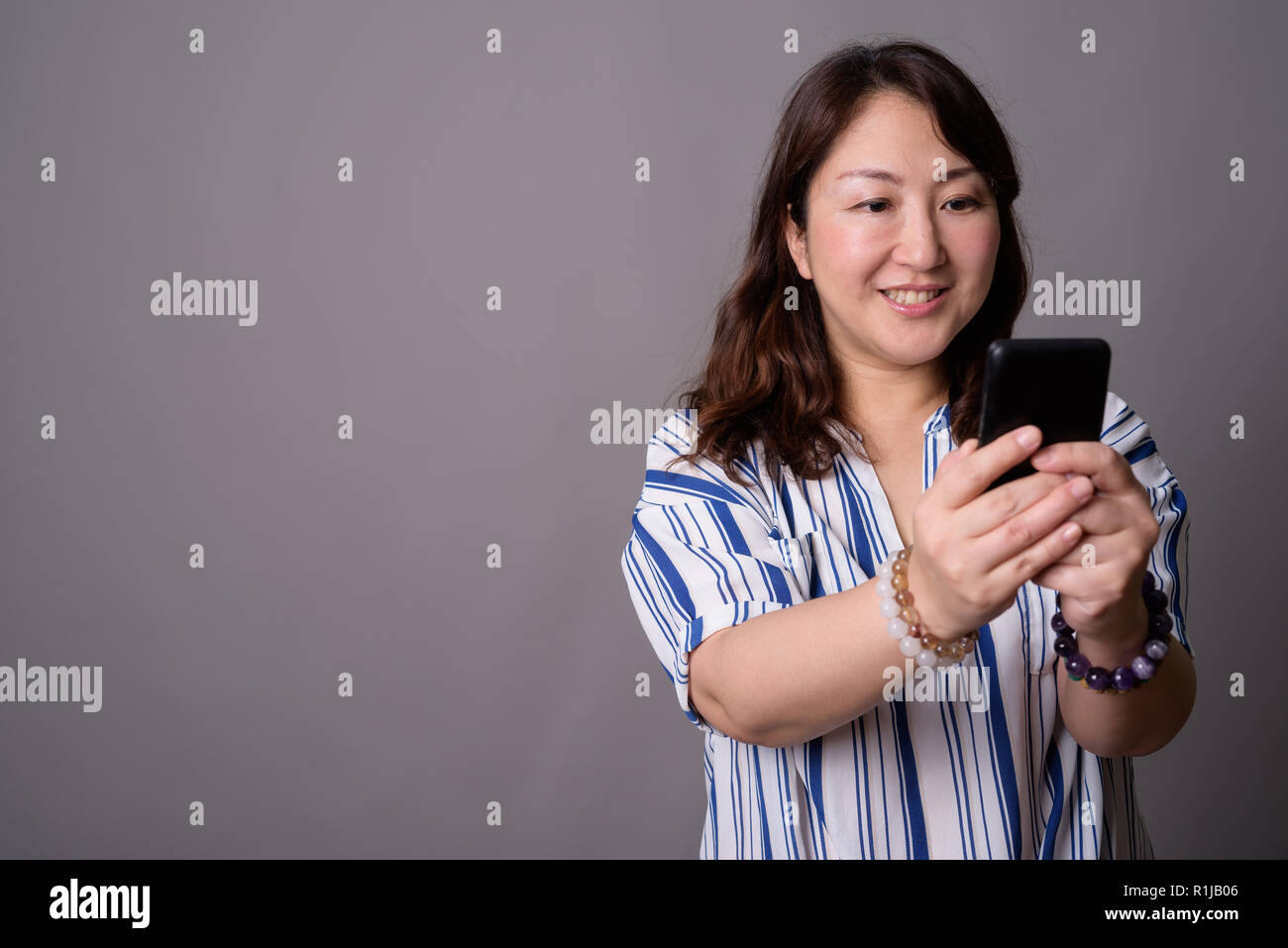 Belle asiatique mature businesswoman using mobile phone Banque D'Images