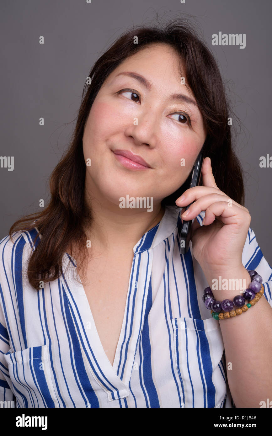 Belle asiatique mature businesswoman talking on phone Banque D'Images