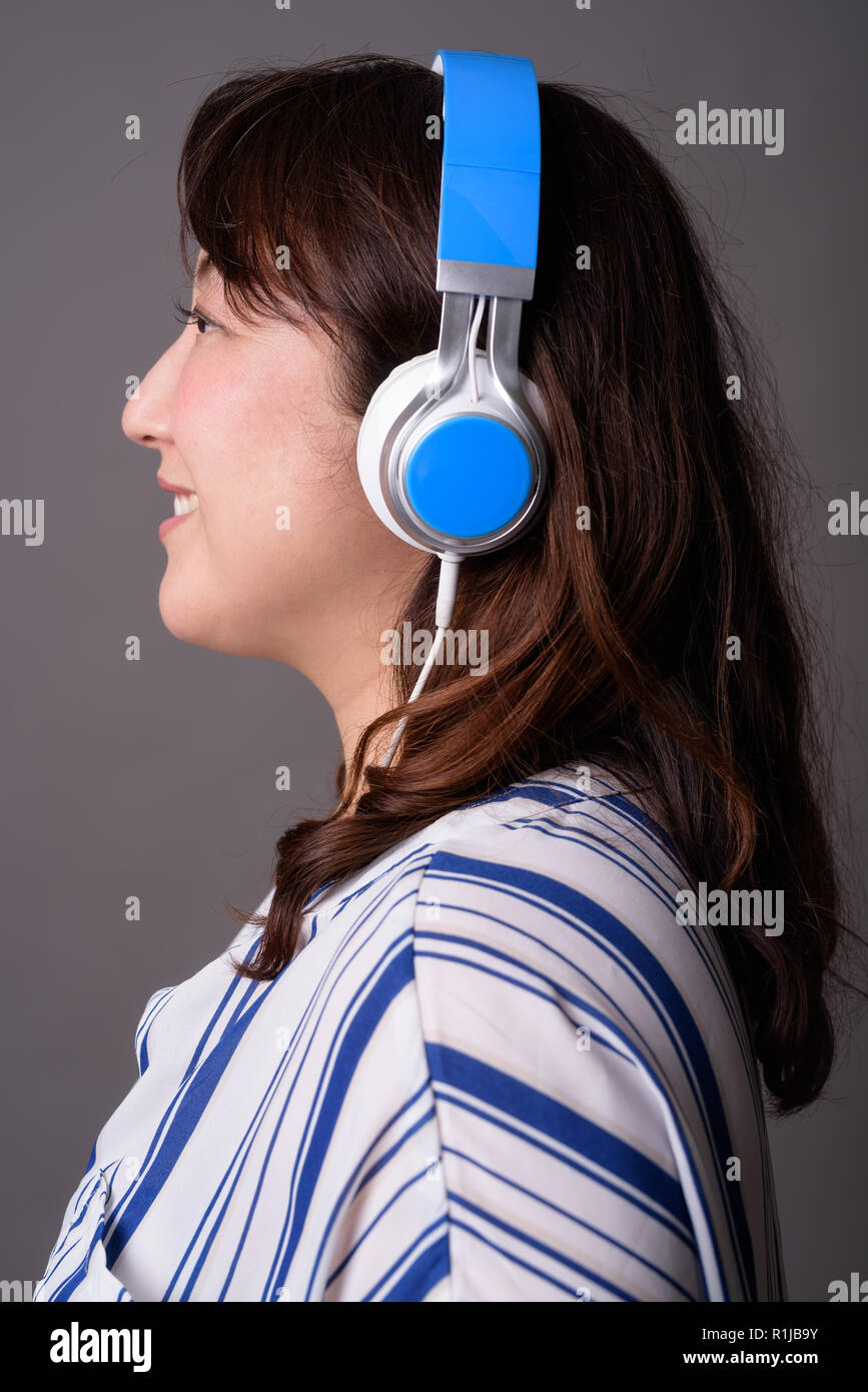 Belle asiatique mature businesswoman listening music with headphones Banque D'Images