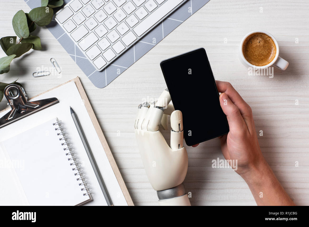 Vue partielle de l'homme d'affaires avec l'aide de main cyborg Smartphone avec écran vide à table avec Coffee cup in office Banque D'Images