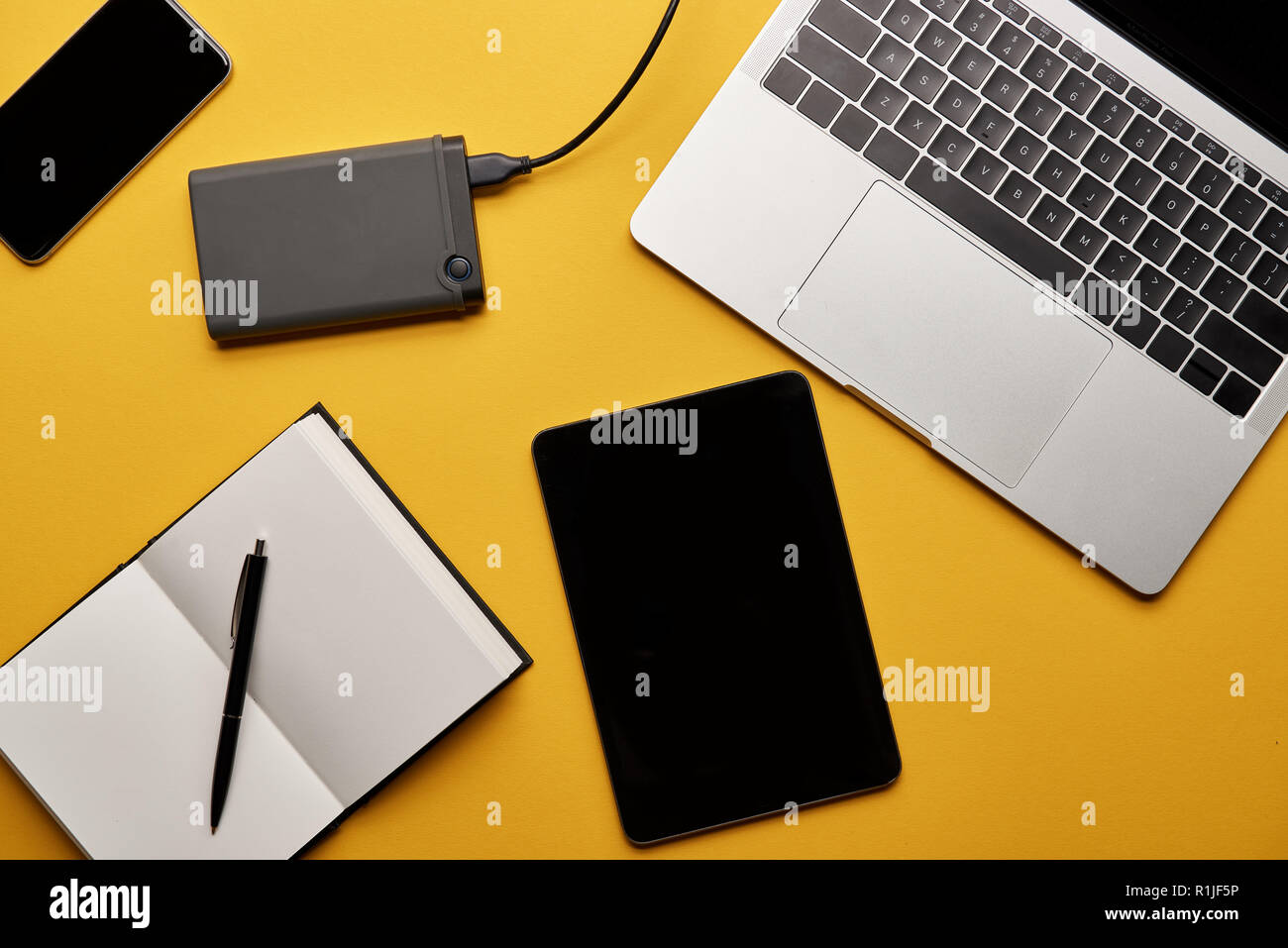 Vue de dessus de divers gadgets avec ordinateur portable ouvert allongé sur la surface jaune Banque D'Images