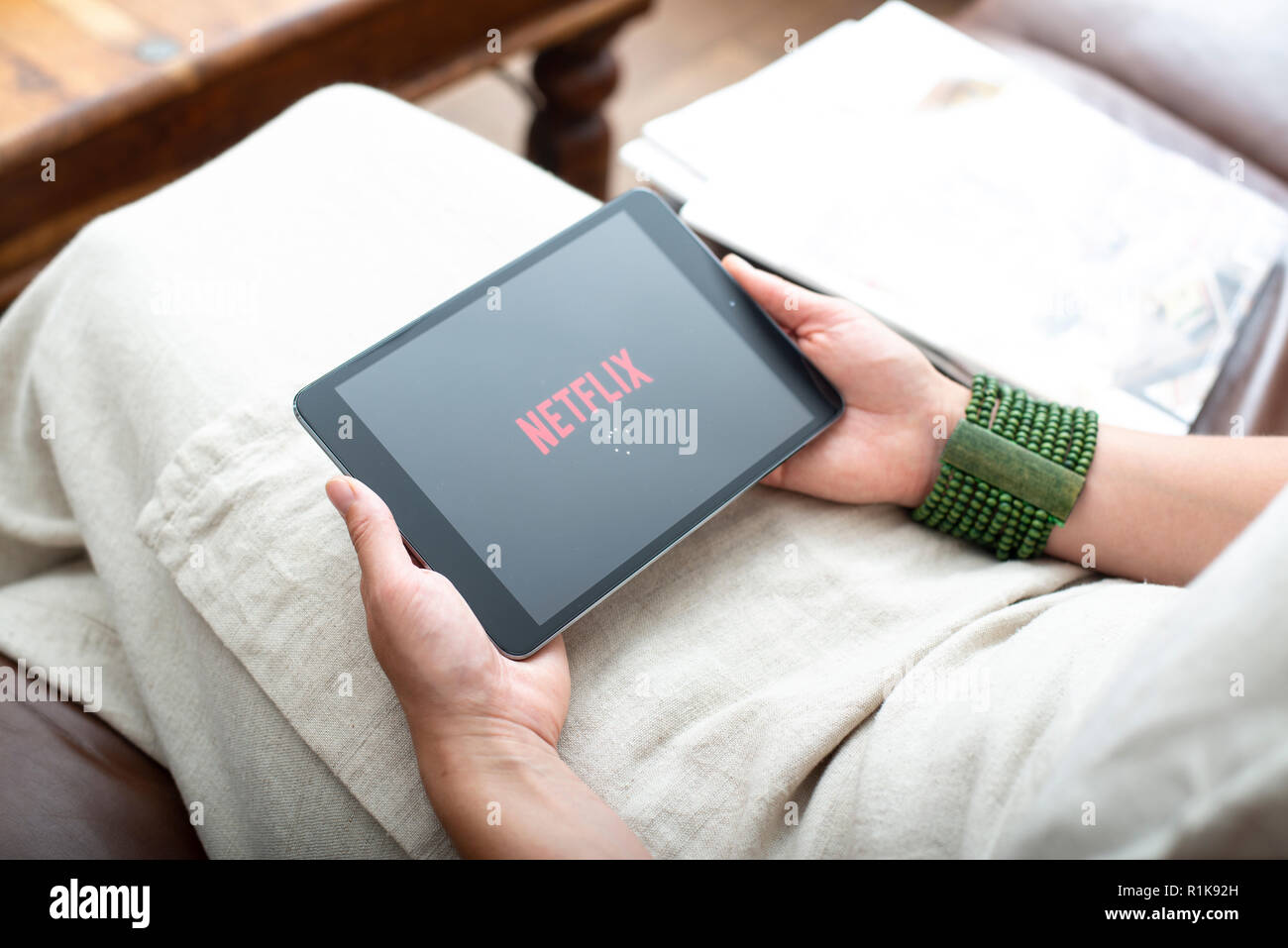 Woman holding ipad streaming Netflix film intérieur sur canapé Banque D'Images