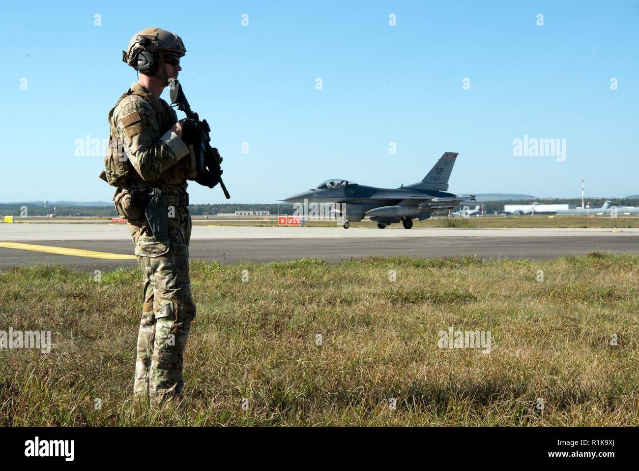 Le sergent de l'US Air Force. Dwight Stalter, 435e Escadron des Forces de sécurité chef d'équipe, monte la garde tandis qu'un pilote de F-16 Fighting Falcon attend son avion à être ravitaillées sur base aérienne de Ramstein, en Allemagne, le 4 octobre 2018. Les membres de la 435ème ESF a participé à Ace tempérées, une preuve de concept de l'exercice mené par la 435ème aile d'opérations air-terre, démontrant les capacités de la force de frappe. Banque D'Images