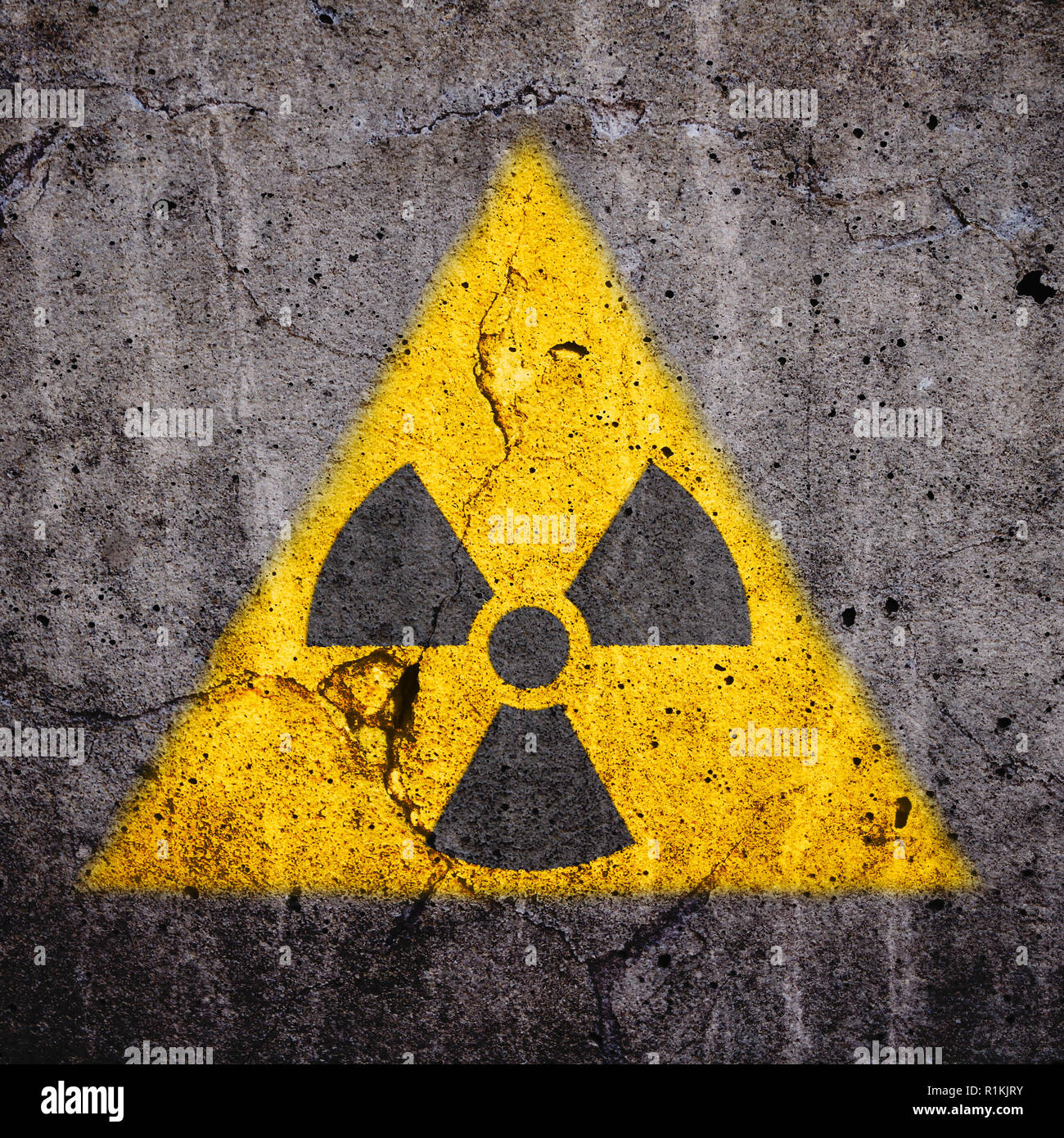 (Radioactifs) Rayonnements ionisants atomique symbole d'avertissement de danger dans la forme jaune triangulaire peint sur un mur de ciment béton fissuré massive avec et da Banque D'Images