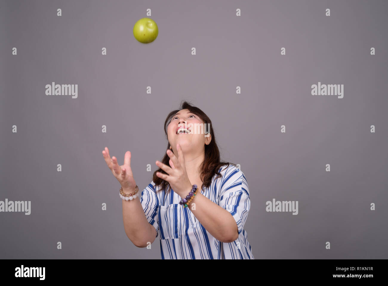 Portrait of mature Asian businesswoman attraper la pomme verte Banque D'Images