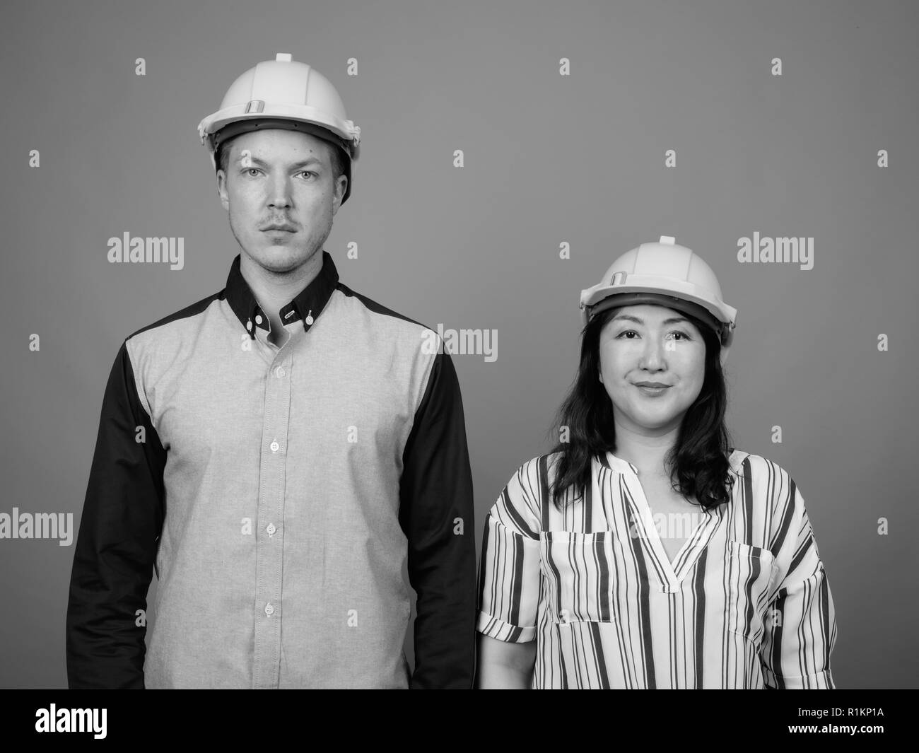 Businessman et mature Asian businesswoman wearing hardhat Banque D'Images