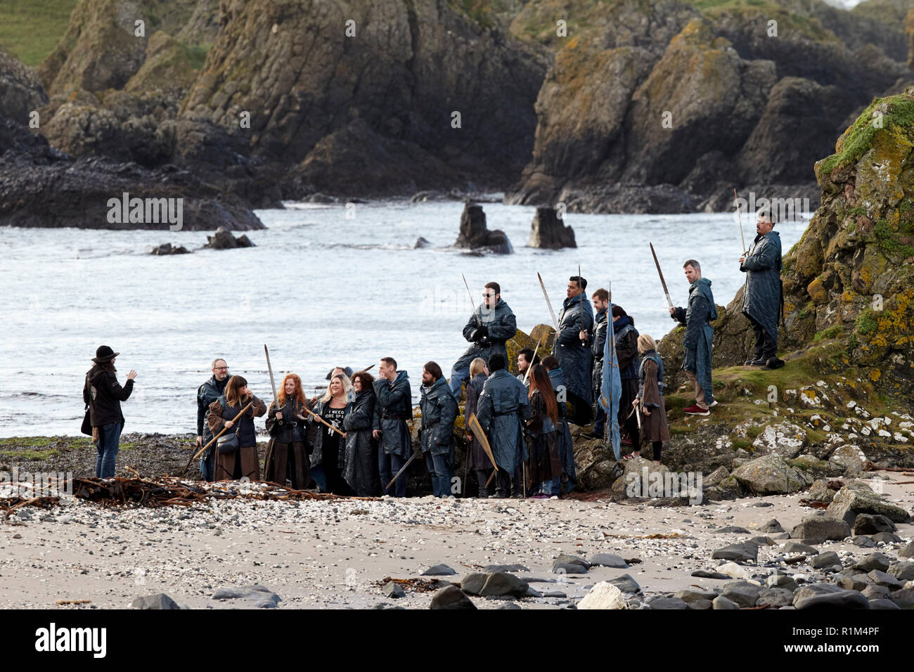 Les touristes portant des costumes holding épées sur un jeu des trônes coach tour guidé à Ballintoy sur le Nord de la côte nord d'Irlande Banque D'Images
