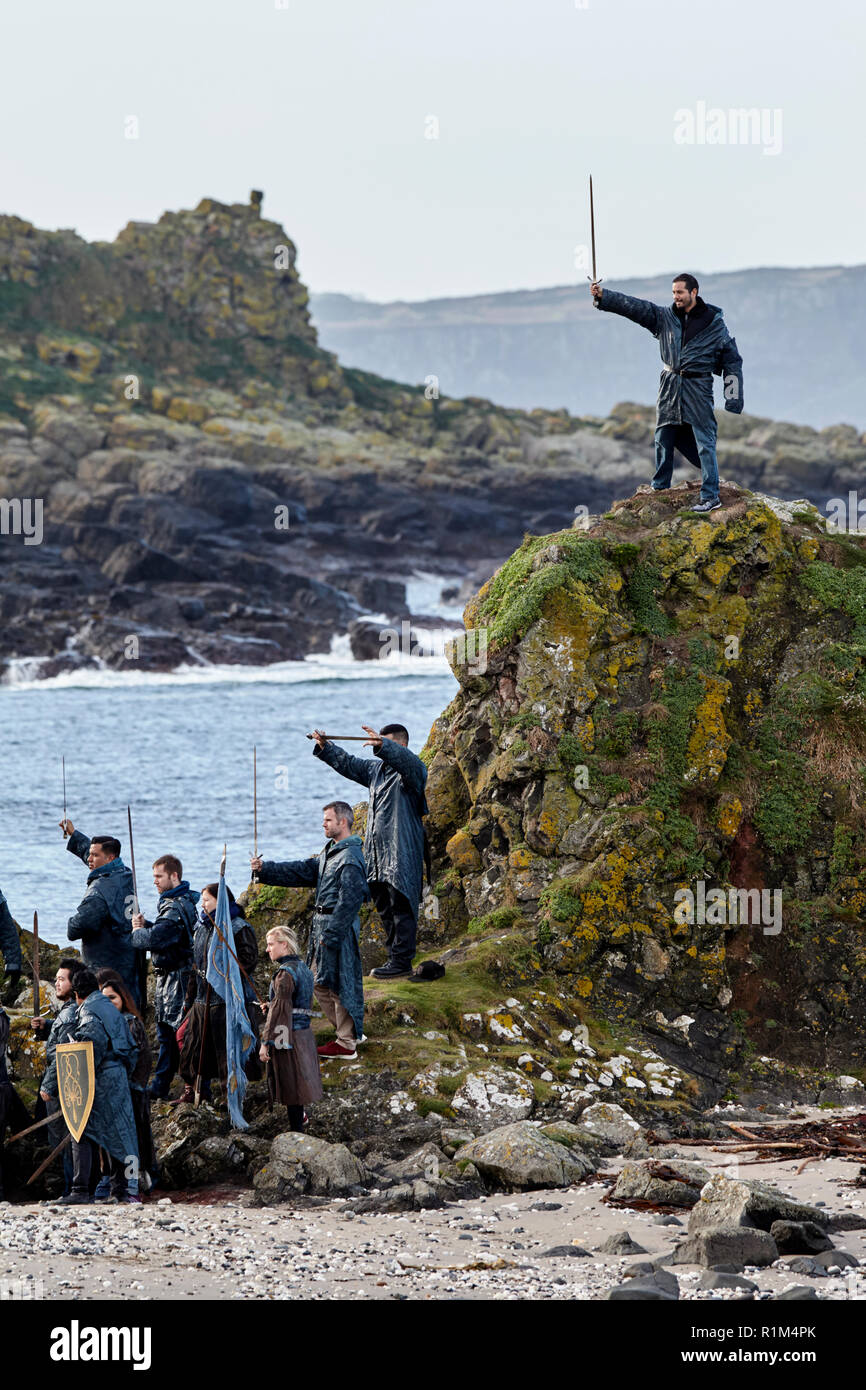 Les touristes portant des costumes holding épées sur un jeu des trônes coach tour guidé à Ballintoy sur le Nord de la côte nord d'Irlande Banque D'Images