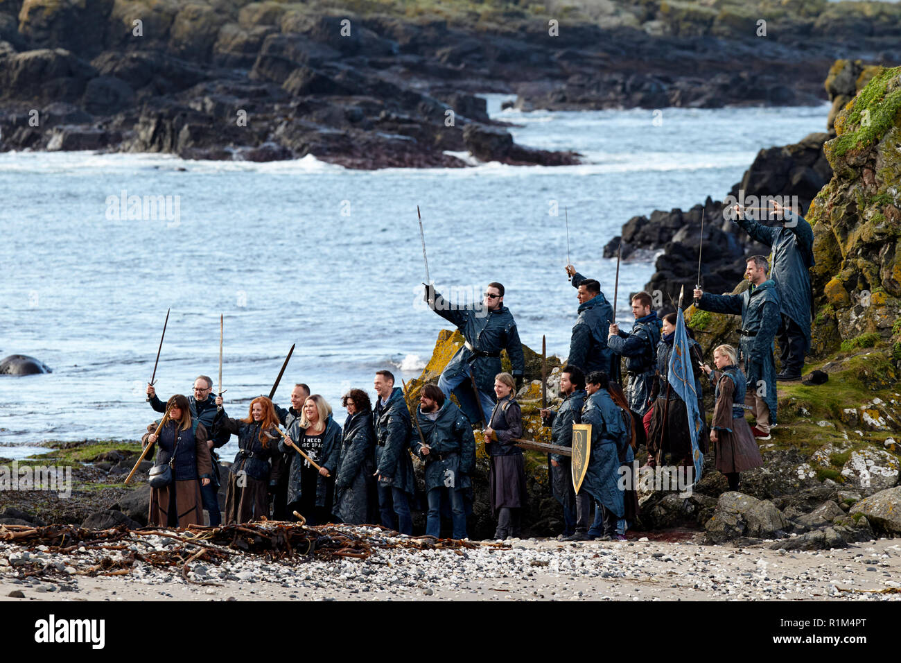 Les touristes portant des costumes holding épées sur un jeu des trônes coach tour guidé à Ballintoy sur le Nord de la côte nord d'Irlande Banque D'Images