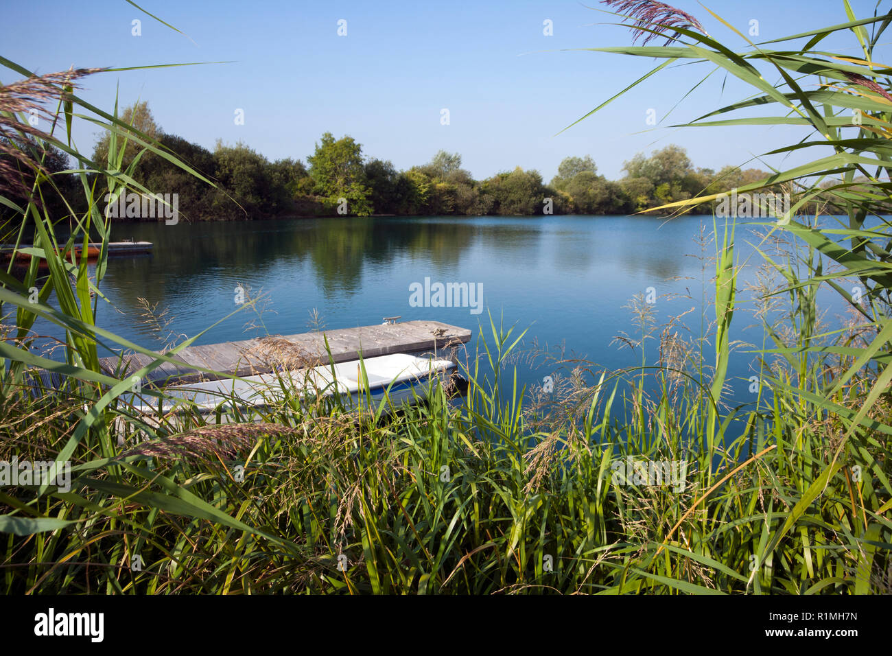 Une barque amarrée par une petite jetée sur un lac dans le soleil d'été Banque D'Images