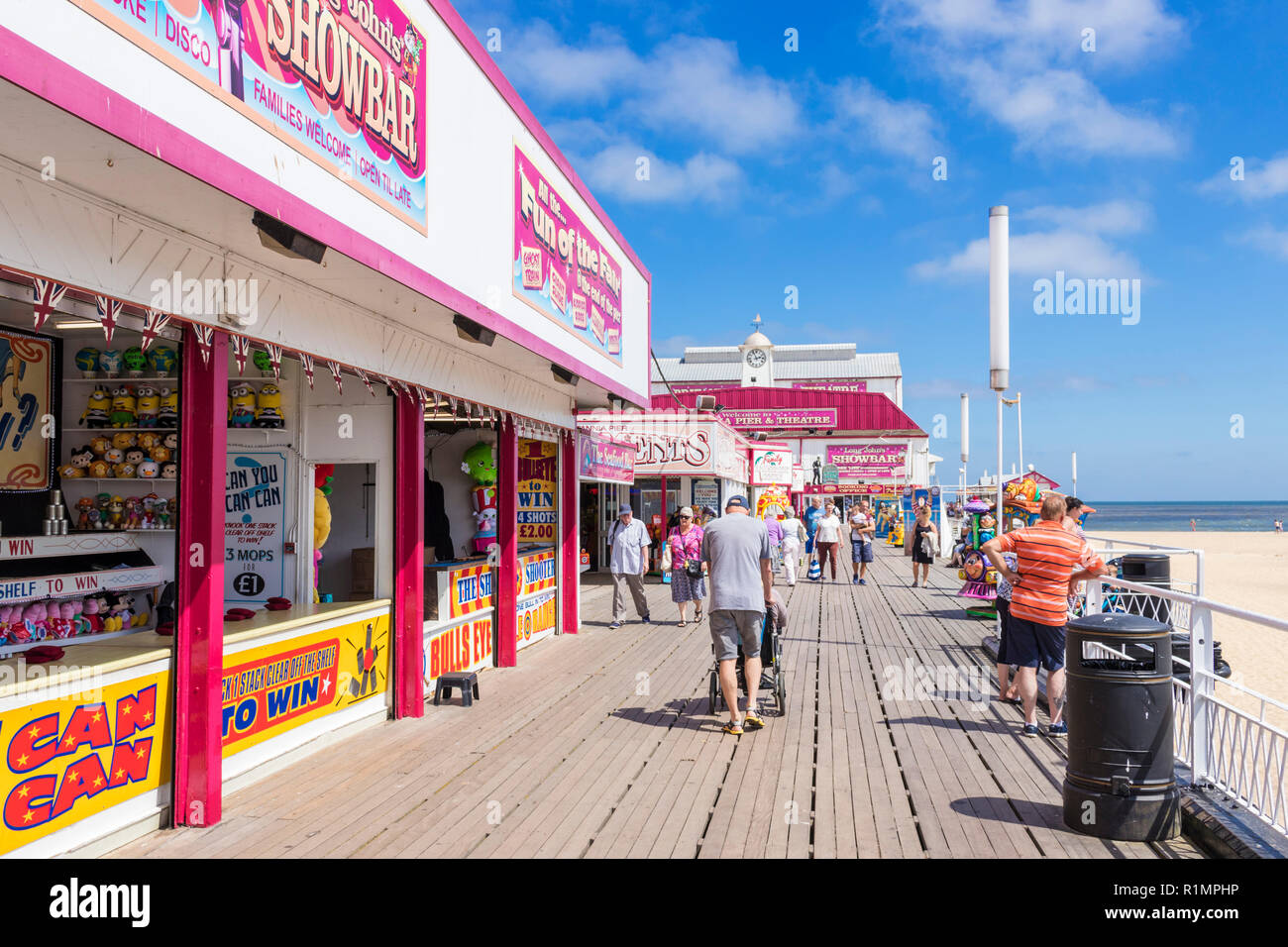 Great Yarmouth Britannia Pier et théâtre de bord de touristes en passant devant des salles de jeux et des manèges Great Yarmouth Norfolk England UK GO Europe Banque D'Images