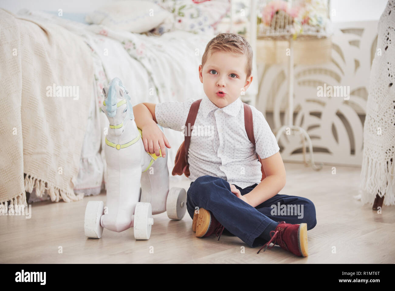 Adorable petit garçon va à l'école pour la première fois. Sac d'école avec l'enfant et le livre. Kid fait un porte-documents, chambre enfant sur un arrière-plan. Retour à l'école Banque D'Images