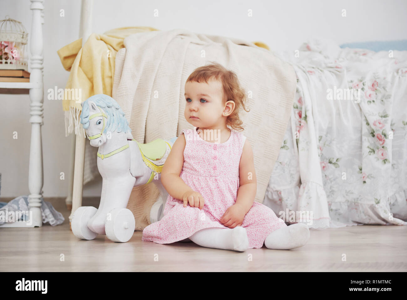 Belle petite fille jouant les jouets. Blonde aux yeux bleus. Chaise blanche. La chambre des enfants. Heureux petite fille portrait. Concept de la petite enfance Banque D'Images