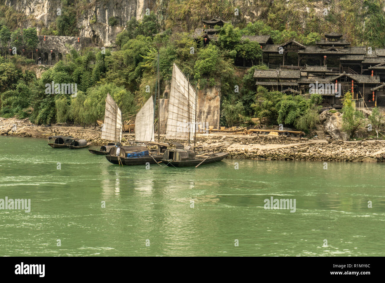Sampans de voiles le long de la rivière Yangtze avec des maisons traditionnelles en arrière-plan Banque D'Images