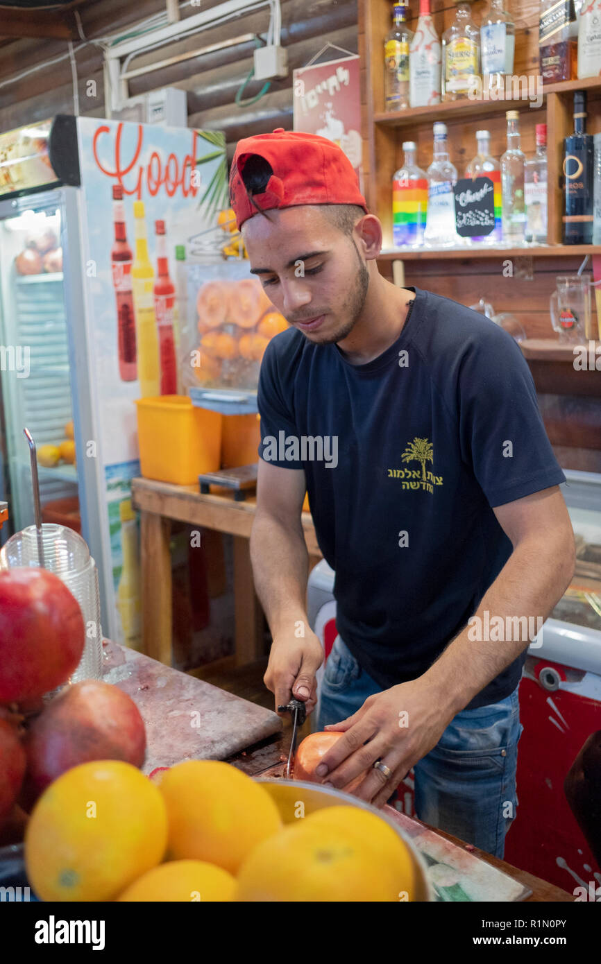 Un jeune Israélien de l'Almog kibbutz couper les grenades à un stand de jus sur la route de Jérusalem. Banque D'Images