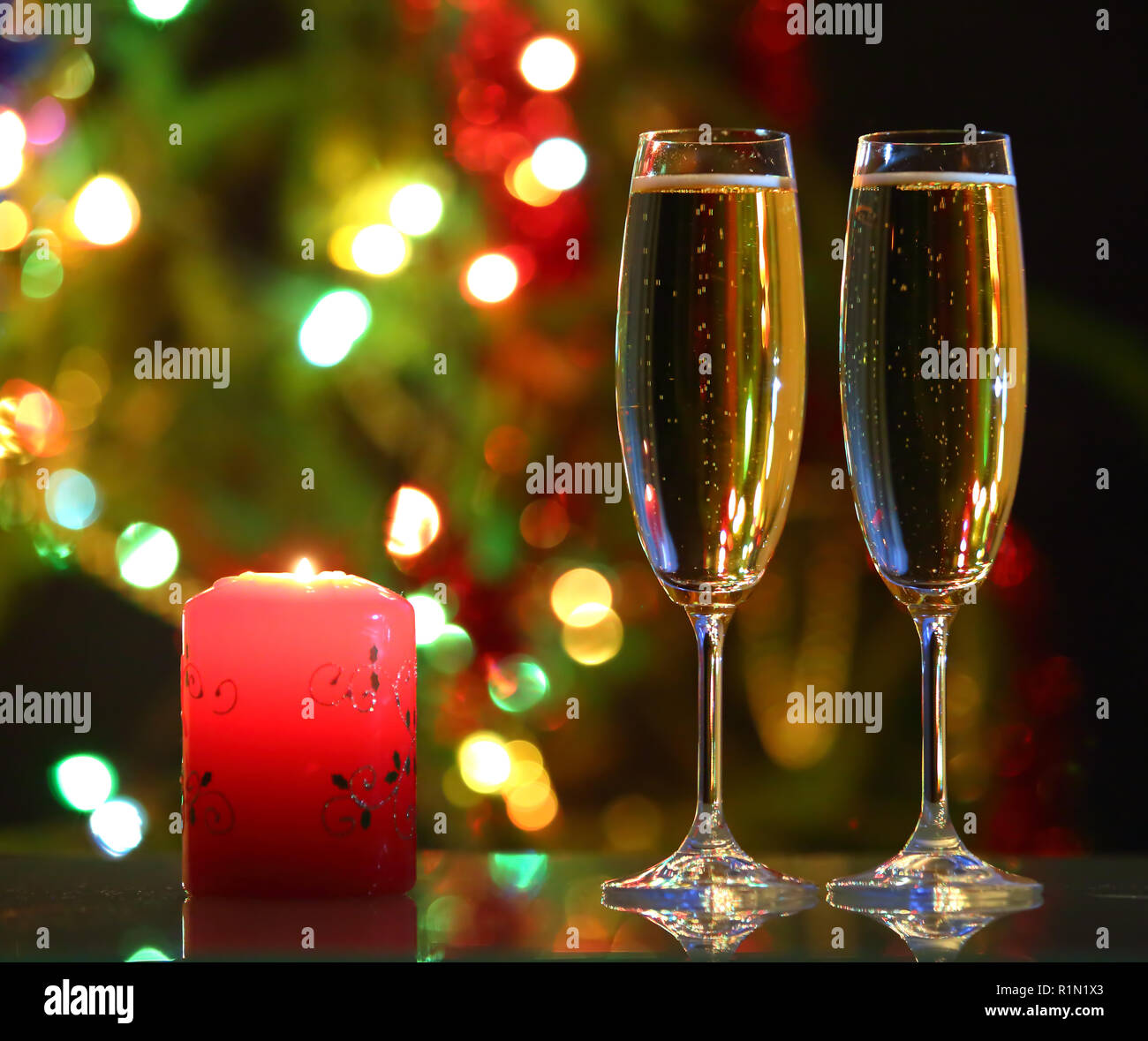 Lunettes avec champagne et bougies contre lumières de fête Banque D'Images