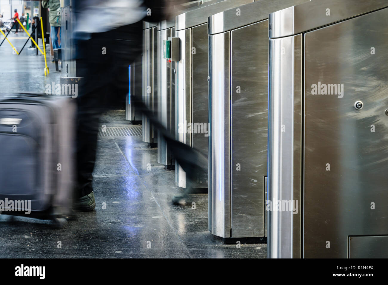 Vue latérale d'un homme avec une valise de matériel roulant en passant par des portes en acier inoxydable d'un ticket de transport public gare à Paris avec effet de flou. Banque D'Images