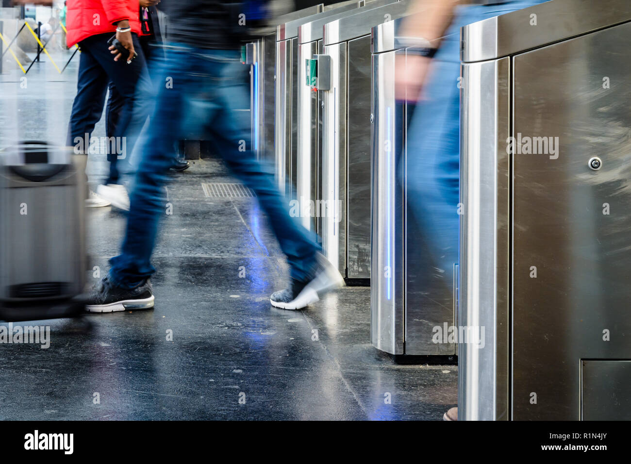 Vue latérale d'un homme avec une valise de matériel roulant en passant par des portes en acier inoxydable d'un ticket de transport public gare à Paris avec effet de flou. Banque D'Images