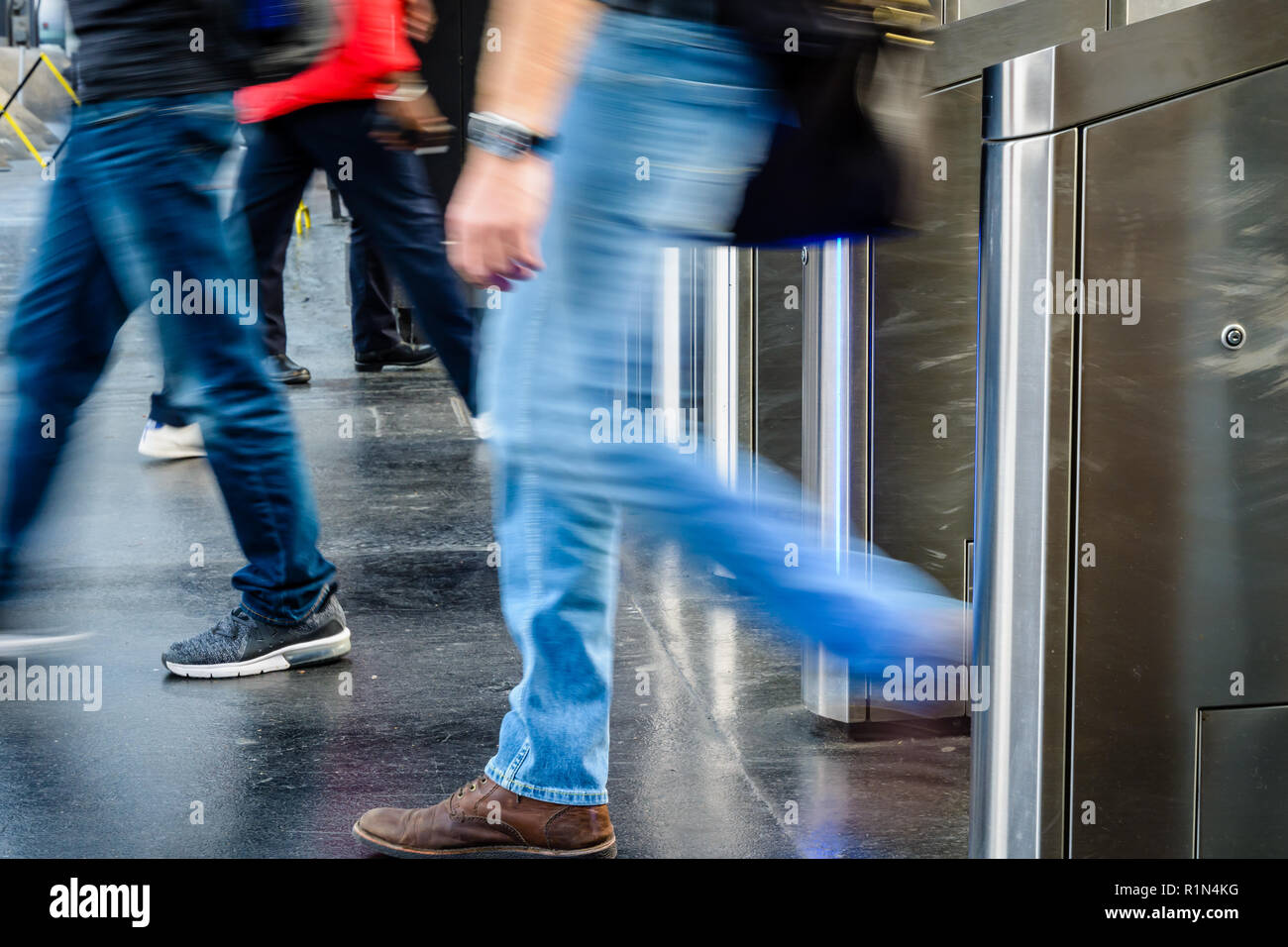 Vue latérale d'hommes en passant par des portes en acier inoxydable d'un ticket de transport public gare à Paris, France, avec le flou. Banque D'Images